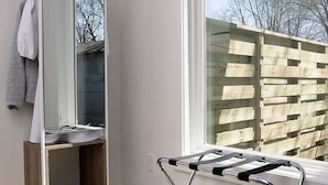 A modern bathroom with a large mirror, a wooden vanity, a towel rack, and a window with a view of trees. - NEW! WhitelineStudio on Ast., Downtown Bentonville new the square (Bentonville)
