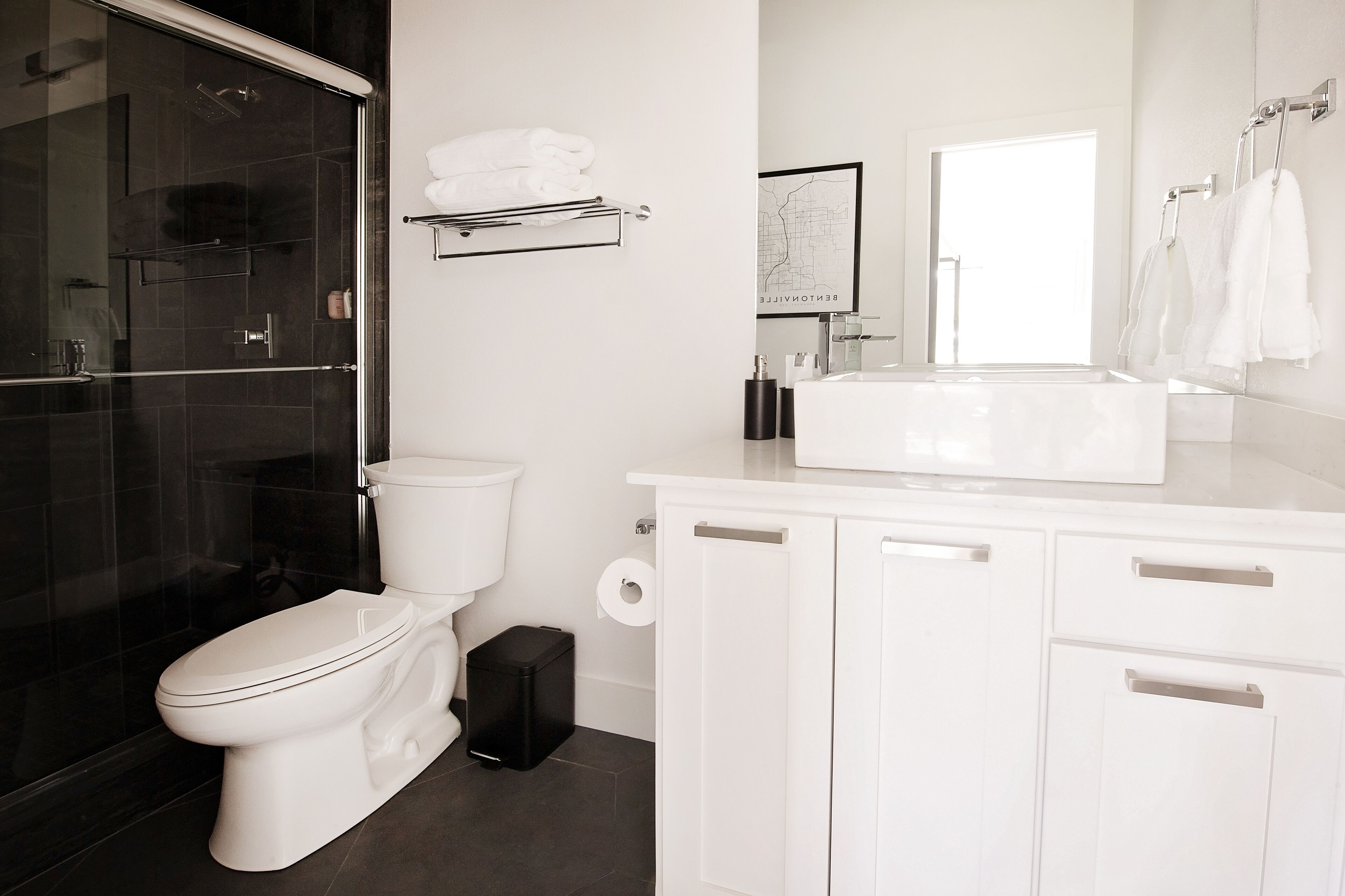 Une salle de bain moderne avec des toilettes, une douche à l’italienne en verre, un lavabo blanc et un miroir.