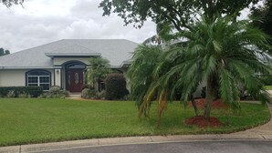 A two-story house with a grey roof, a red front door, and a well-maintained lawn. - Wonderful private Lake house by the canal of lake Arietta (Auburndale)