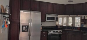 Una cocina con armarios de madera oscura, un refrigerador de acero inoxidable, un microondas, una estufa y un dispensador de agua.