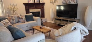 Una sala de estar con un sofá, una mesa de centro, una chimenea, un televisor y un jarrón decorativo.