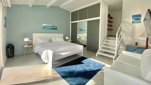 Una habitación de hotel moderna con una cama grande, un escritorio, una silla y una escalera que lleva a un nivel superior.