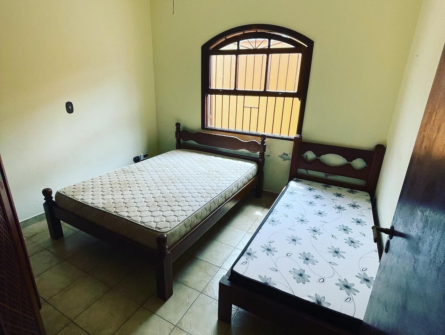 Una habitación pequeña con dos camas individuales, una con cabecera de madera y la otra con edredón estampado.