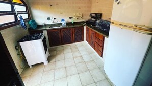 A compact kitchen with a gas stove, a sink, and a refrigerator. - Vacation home in Peruíbe (Peruibe)