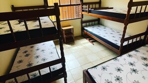 A dormitory room with bunk beds, a small wooden stool, and a window with a wooden lattice. - Vacation home in Peruíbe (Peruibe)