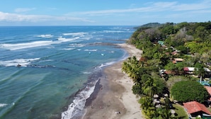 A beach with clear waters, a sandy shore, and lush greenery. - Flex House – Full Home with Pool and Guest House, Close to the Beach (Esterillos Oeste)