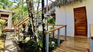 A wooden deck leading to a building with a thatched roof and a wooden door. - Flex House – Full Home with Pool and Guest House, Close to the Beach (Esterillos Oeste)