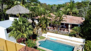 A residential area with a swimming pool, surrounded by lush greenery and palm trees. - Flex House – Full Home with Pool and Guest House, Close to the Beach (Esterillos Oeste)