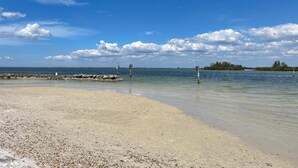 A beach with clear skies, calm water, and a rocky breakwater. - Adorable Waterfront guest house (Apollo Beach)