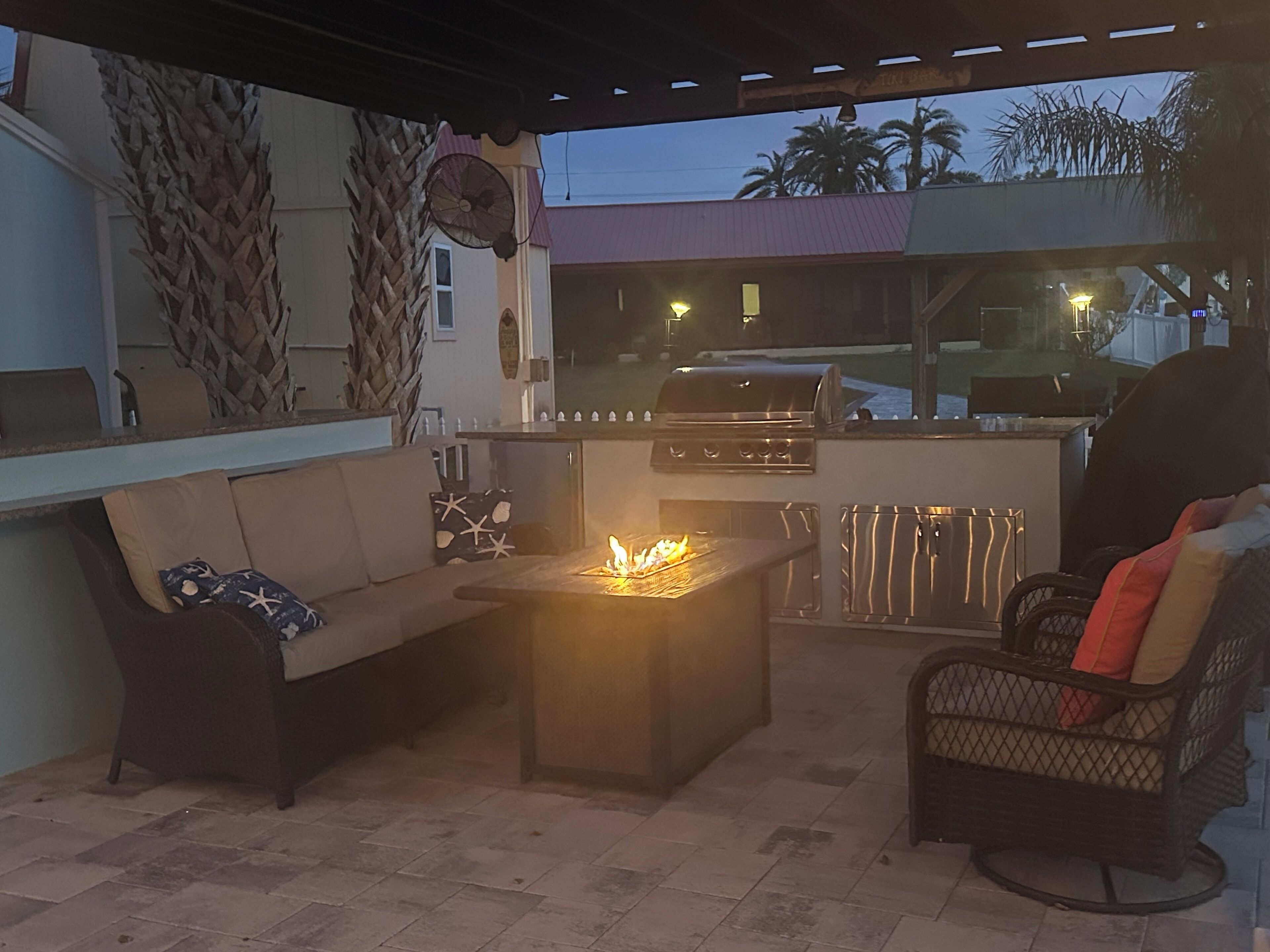 An outdoor patio area with a grill, a sofa, and a chair.