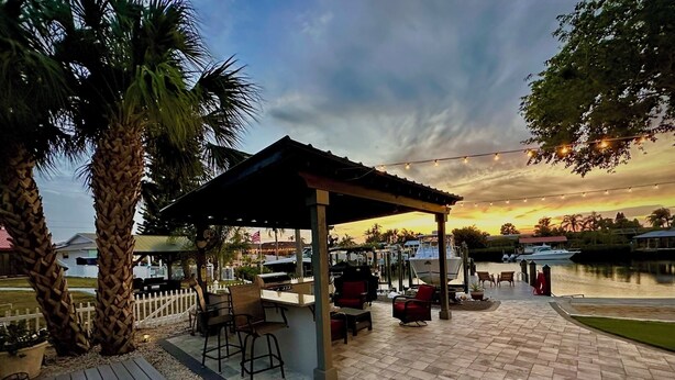 An outdoor patio with a covered seating area, a grill, and a view of the water and boats. - Adorable Waterfront guest house (Apollo Beach)