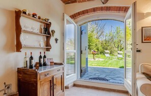 A room with a wooden cabinet, wine bottles, and a glass door leading to a garden. - 1 bedroom cozy home in Ferrere (Ferrere)