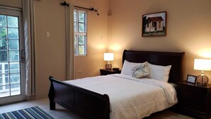 A bedroom with a large bed, two bedside tables with lamps, a window with curtains, and a painting on the wall. - Green Space, Santa Cruz Valley, Trinidad 2 (La Pastora Settlement)