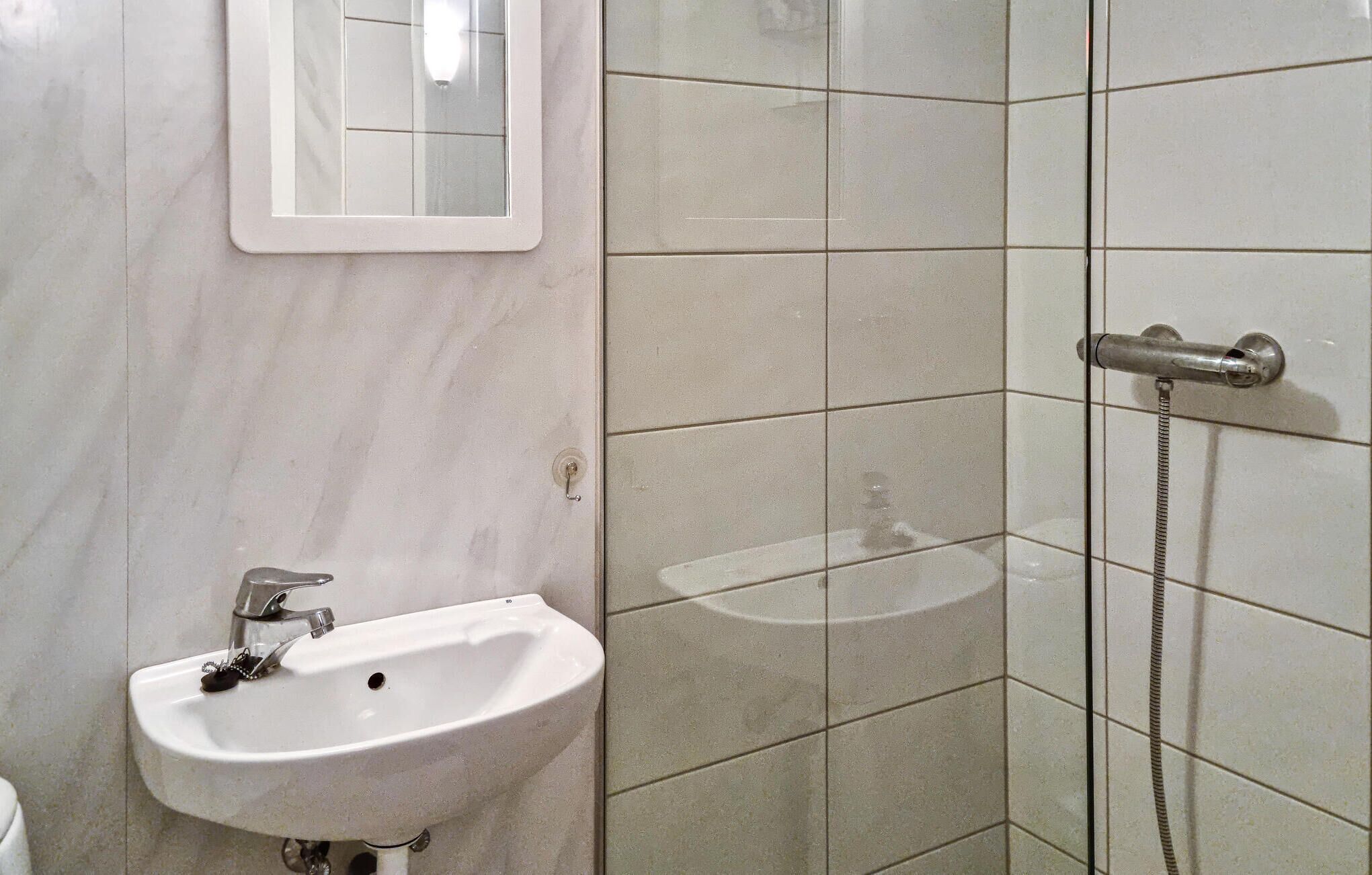 Un baño con lavamanos, espejo y zona de ducha.
