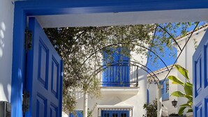 A white building with blue doors and windows, a staircase leading to a balcony, and potted plants. - Amazing 6 bed villa with private pool and views (Almuñecar)