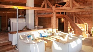 Interior de una cabaña de madera con cocina, una mesa de comedor y un conjunto de sofás.
