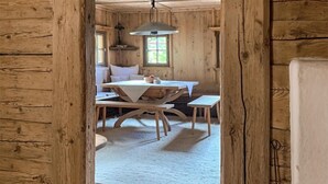 Una habitación rústica de madera con una mesa de comedor, bancos y una lámpara colgante.