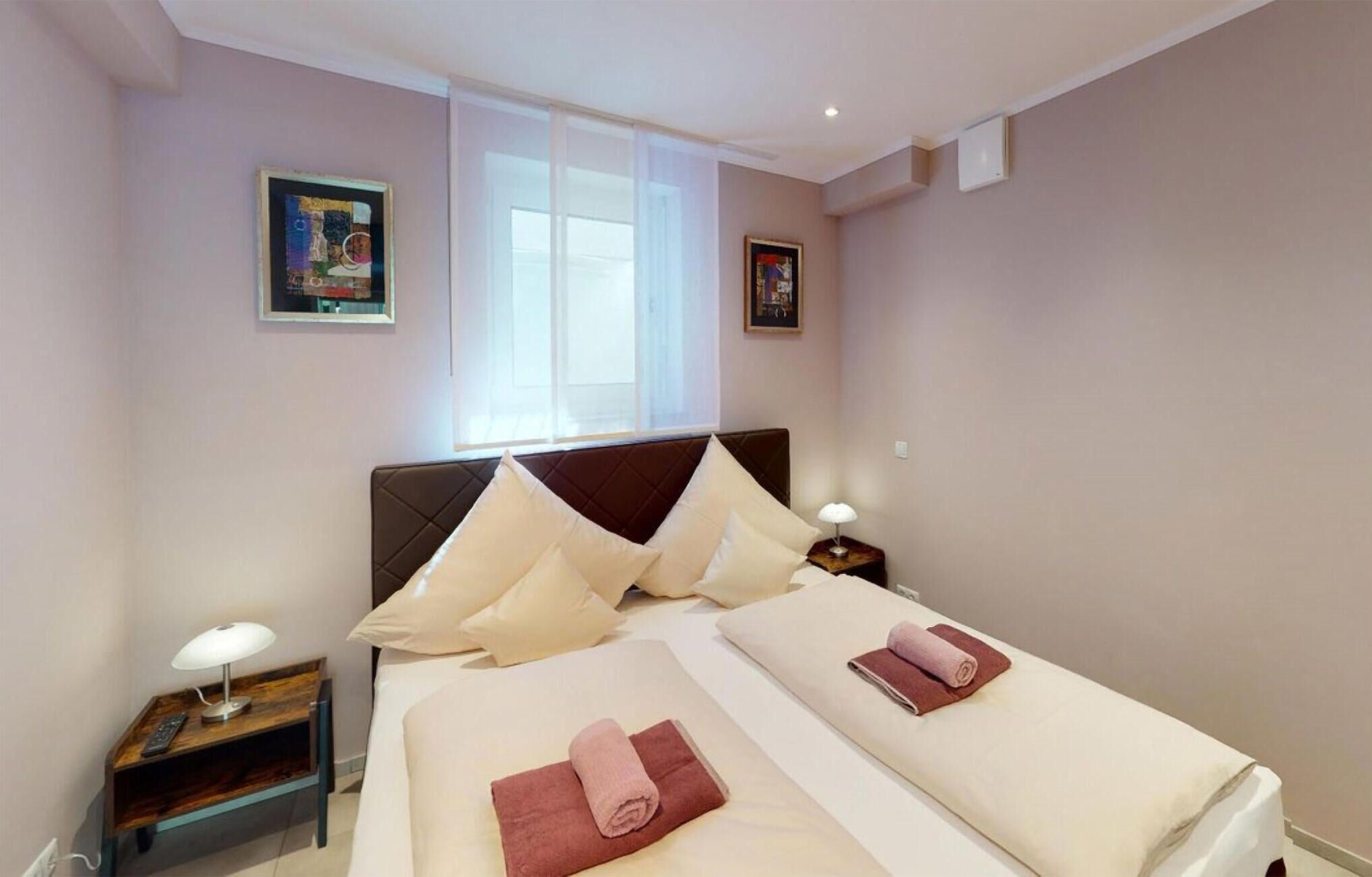 Ett hotellrum med två sängar, ett fönster och konstverk på väggarna.
