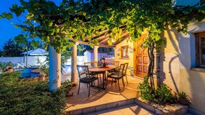 A patio with a table and chairs, a pergola with vines, and a pool in the background. - Pet friendly home in Veliki Vareski (Veliki Vareski)