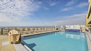 Relax by the ocean with a refreshing dip in the pool, surrounded by lounge chairs and umbrellas.