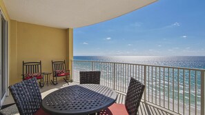 Enjoy the ocean view from this balcony with two comfortable chairs and a table.