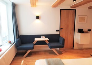 A cozy room with a dark blue sofa, a small wooden table, a white cabinet, and a wooden door. - Stay in our centrally located 18th century house. Contactless stay possible. (Amsterdam)