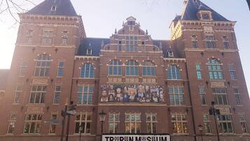 A historic building with a prominent entrance and a sign reading 'Tropen Museum.'