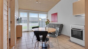Une cuisine moderne avec une table ronde, deux chaises, un canapé et un four encastré.