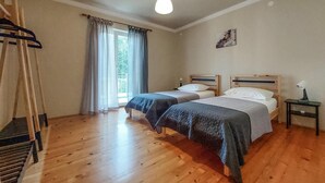 Ein Zimmer mit zwei hölzernen Betten, einer Holzbank, einer Pendelleuchte und einem Fenster mit Vorhängen.