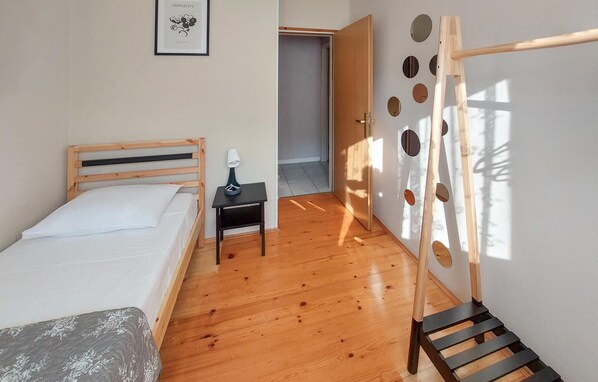 Un dormitorio con una cama de madera, una mesita de noche con lámpara, una puerta con detalles circulares y una escalera.