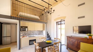 Una cocina moderna con comedor, televisión y escalera que sube a un nivel superior.
