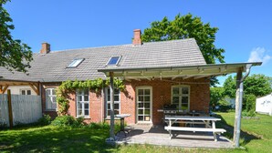 Ein Backsteinhaus mit überdachter Veranda und Picknicktisch.