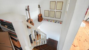 Eine Treppe mit zwei Gitarren, die an der Wand lehnen, einem weißen Geländer und einer Reihe gerahmter Dokumente an der Wand.