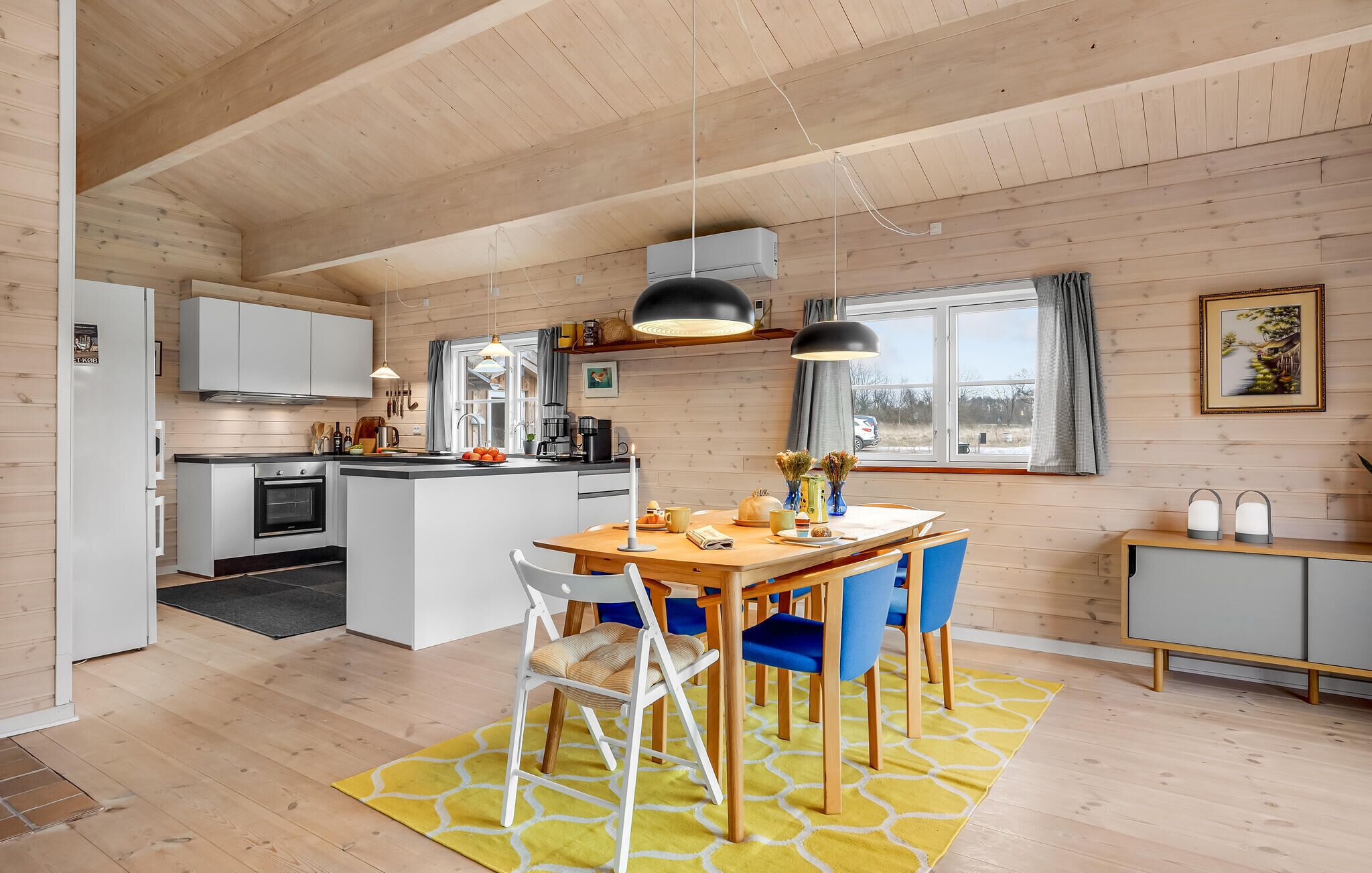 A modern kitchen with white cabinets, a wooden island, and a dining area with blue chairs.