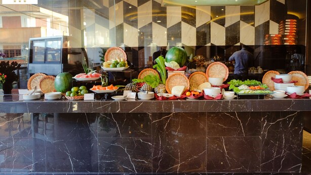 Un mostrador de buffet con diversas frutas, verduras y platos.