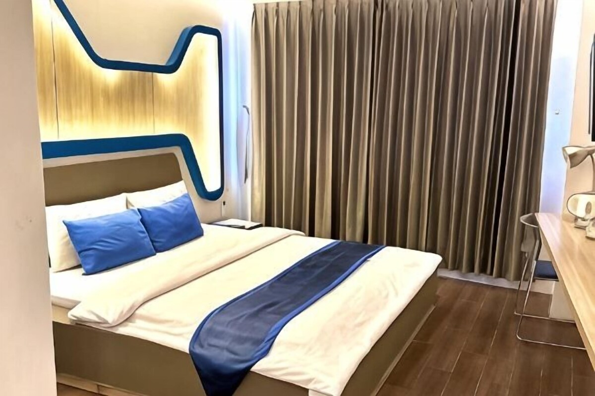 A hotel room with a bed, curtains, and a nightstand.