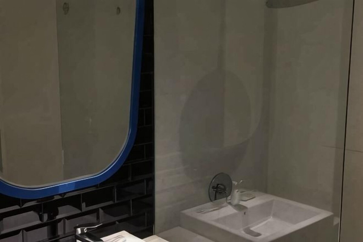 A bathroom with a mirror, a sink, and a shower area.