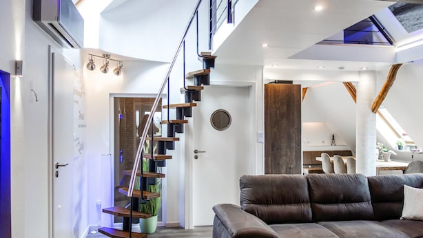 Un interior moderno con una escalera, una sala de estar con sofá y un comedor.