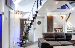 Ein modernes Interieur mit Treppe, einer Sitzecke mit Sofa und einem Essbereich.
