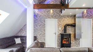 Una sala de estar acogedora con pared de piedra, chimenea y techo moderno estilo loft.