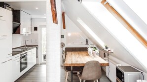 Una cocina moderna con armarios blancos, una mesa de comedor de madera y un tragaluz.