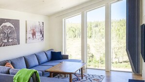A modern living room with a large window, a sofa, a coffee table, and artwork on the wall.