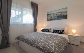 A hotel room with a bed, a painting on the wall, and a window with curtains. - Gorgeous apartment in Okrug Gornji (Okrug Gornji)