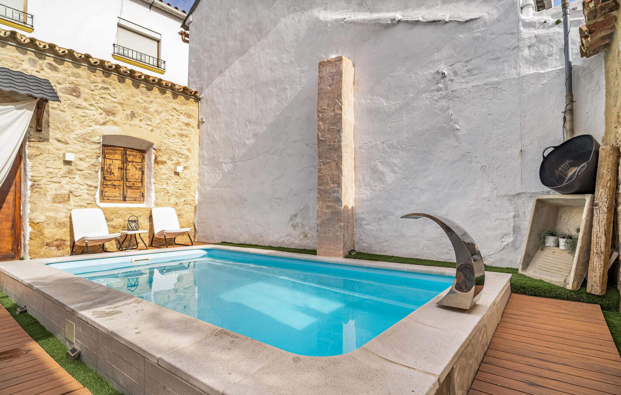 A swimming pool with a stone wall and a wooden deck.