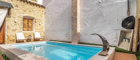 A swimming pool with a stone wall and a wooden deck.