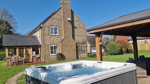 A stone house with a hot tub, outdoor seating, and a covered patio area.
