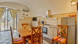 A compact kitchen with a stone wall, a built-in stove, and a refrigerator. - Awesome home in Modica (Modica)