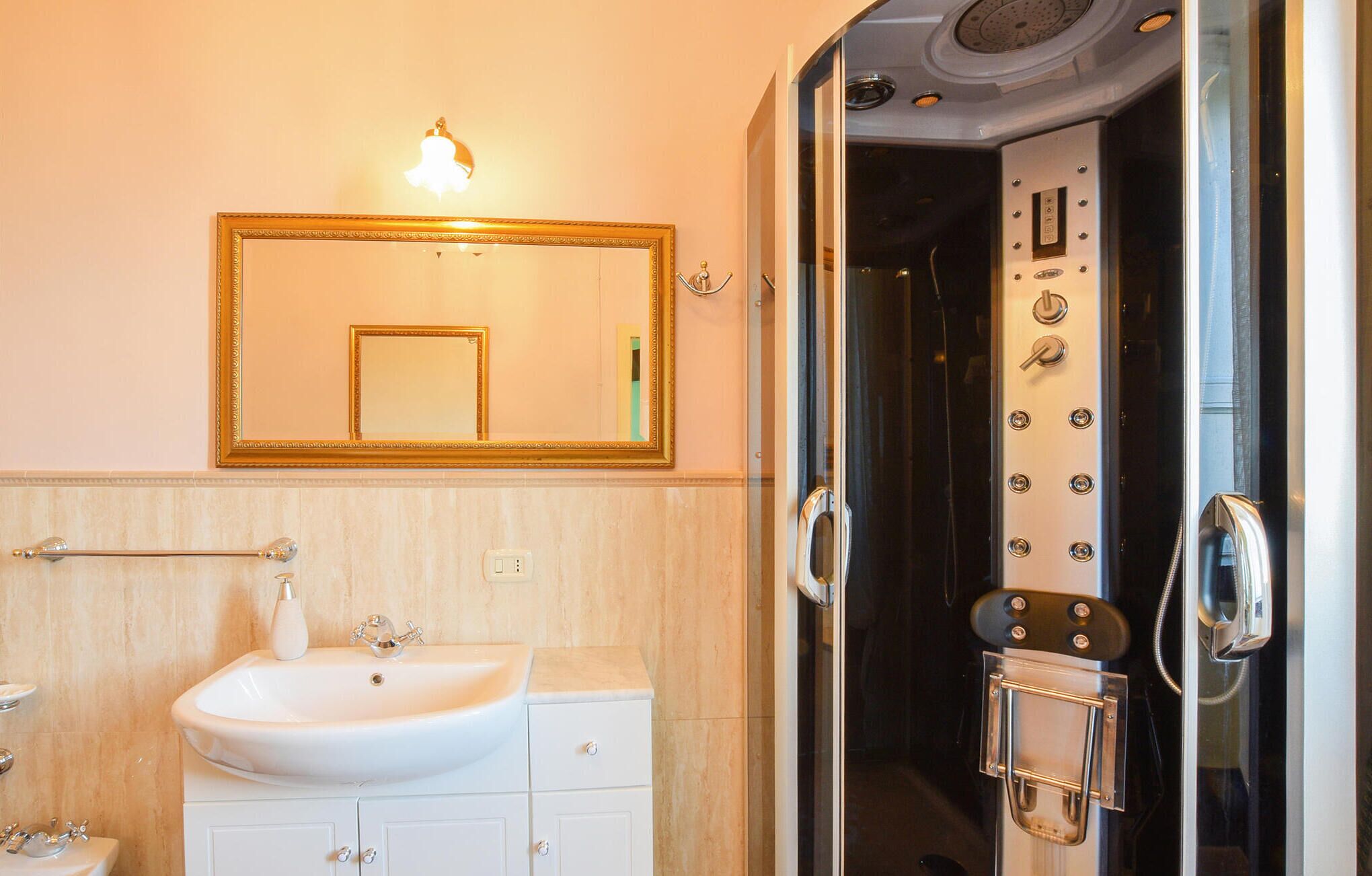 A bathroom with a white sink, a mirror, and a shower with a glass door.