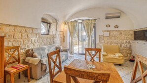 A cozy living room with stone walls, a wooden dining table, and a sofa. - Awesome home in Modica (Modica)