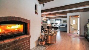 A cozy living room with a brick fireplace, a dining area, and a kitchen in the background. - Pet friendly home in Perstorp with WiFi (Perstorp)